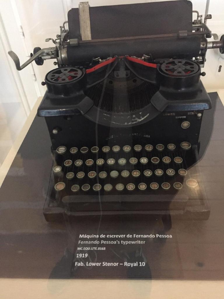 Máquina de escrever Royal 10, preta e de estrutura maciça, de 1919, exposta dentro de uma vitrina, na Casa Fernando Pessoa
